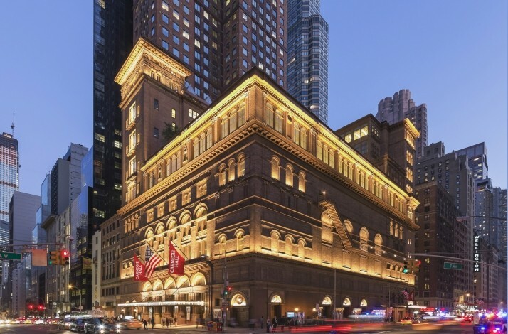 Exterior shot of Carnegie Hall in New York City at dusk, showcasing its architecture amidst the urban landscape.