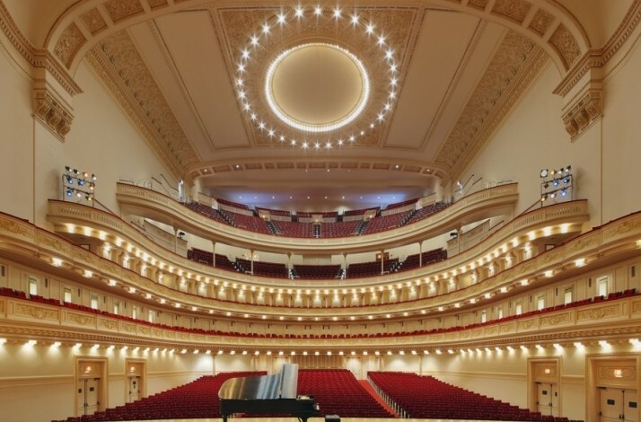 An empty concert hall with a piano on the stage at Carnegie Hall.