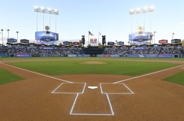 Dodger Stadium's field-level view from home plate, featuring the infield diamond, outfield scoreboard, and surrounding sponsor signage.