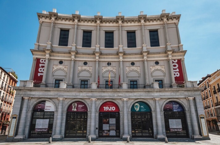 Exterior of Teatro Real in Madrid, showcasing its grand neoclassical façade and historical banners