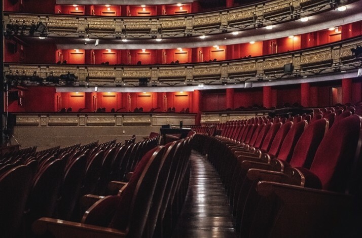 Luxurious interior view of Teatro Real's red-and-gold auditorium with curved balconies and plush seating