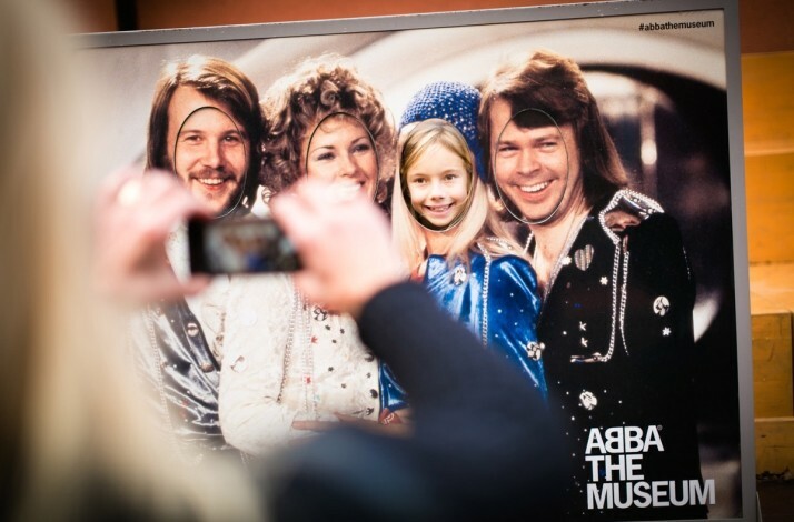 A person takes a photo of an ABBA group cutout at ABBA The Museum.