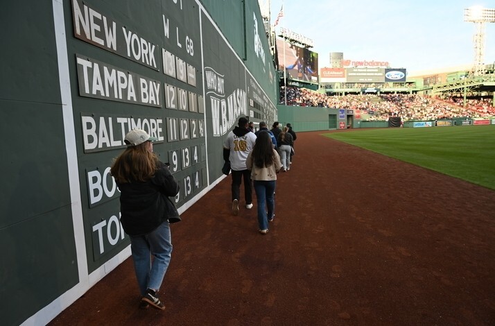 Walking along Fenway Park Green Monster wall tour.