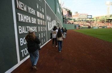 Walking along Fenway Park Green Monster wall tour.