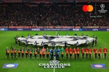 Teams and kids lined up with the iconic UEFA Champions League star ball display on the field
