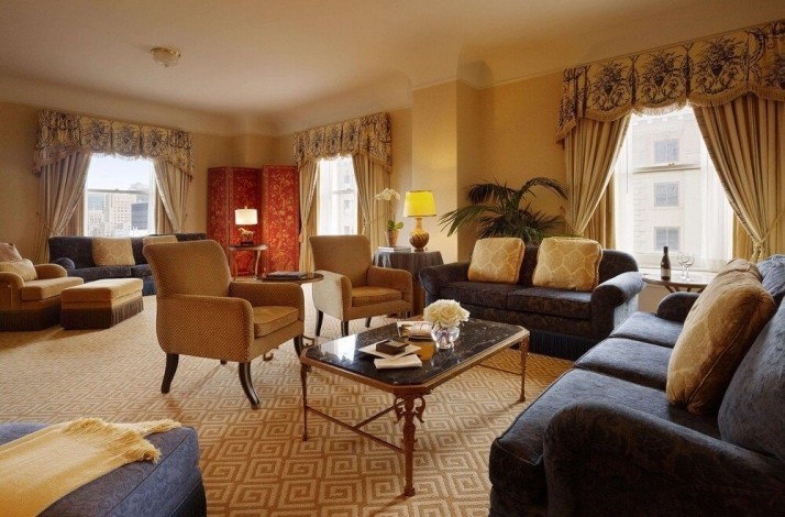 Living room at one of the suites of the Fairmont San Francisco hotel. The room has several couches and armchairs in blue-beige colors.