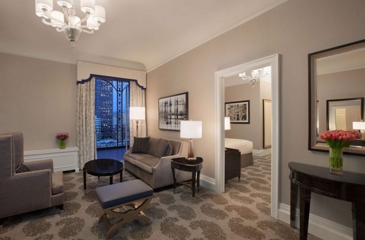 Living room at one of the suites of the Fairmont San Francisco hotel. The room is fully furnished in gray-beige colors and has balcony access. 