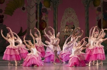Ballerinas in pink tutus pose in a semicircle around a central dancer on a candy-themed stage.