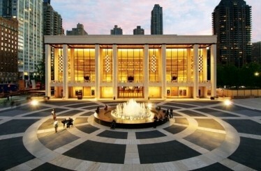 Lincoln Center's David H. Koch Theater illuminated at dusk, with its iconic fountain and plaza in the foreground.