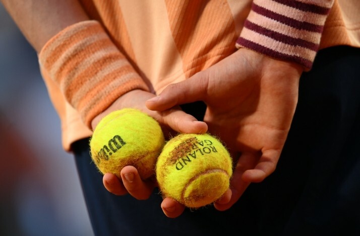 Wilson Roland Garros tennis balls in hands behind back.