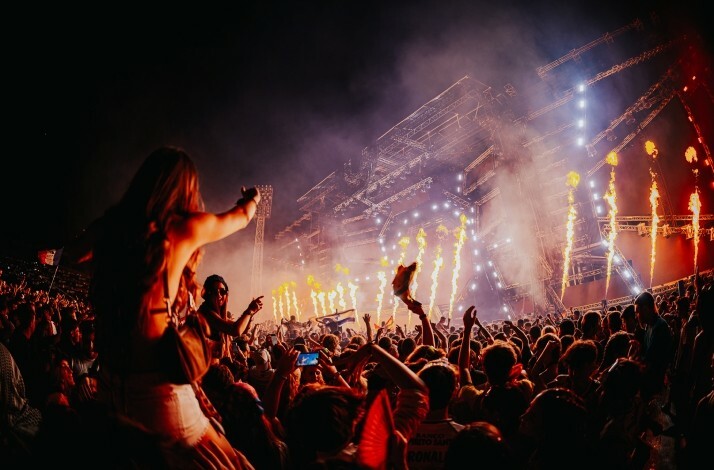 Large crowd of people with their hands raised, enjoying an Ultra Europe performance at night.