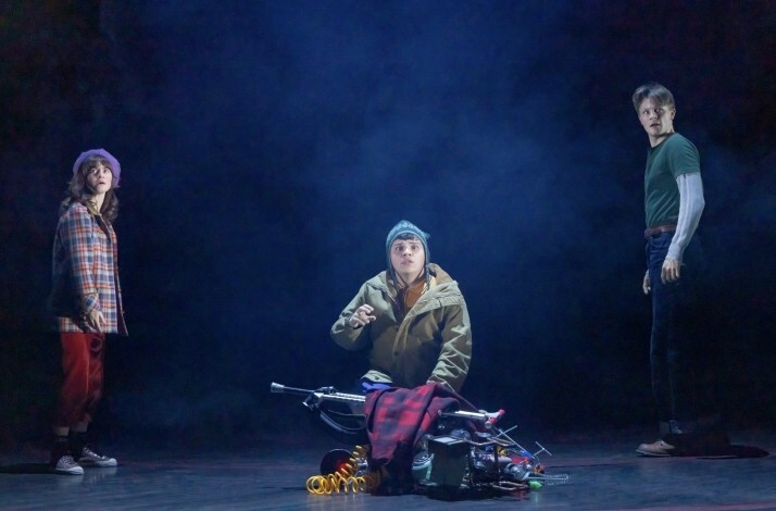 Scene from the Broadway's Stranger Things: The First Shadow performance: 2 boys and a girl look at something in the dark with a terrified look on their faces.