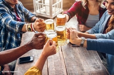 A group of people clinking glasses of beer. © Davide Angelini
