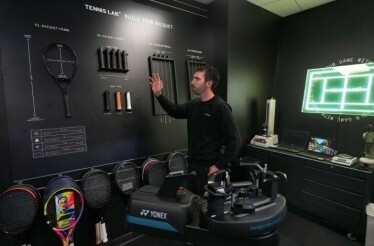 A person demonstrating tennis bats and other items displayed for AO Championships.