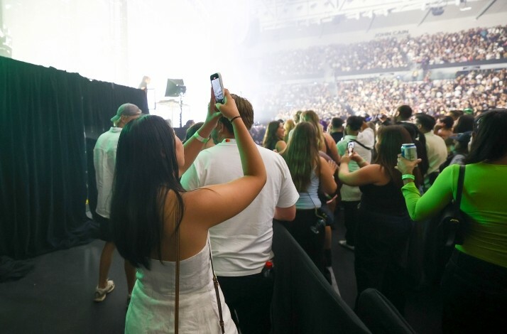 A girl taking a picture at Australia Arena, fully crowded.