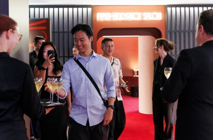 A man takes a glass of champagne from a waiter’s tray at Rod Laver Arena in Melbourne.