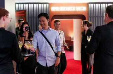 A man takes a glass of champagne from a waiter’s tray at Rod Laver Arena in Melbourne.