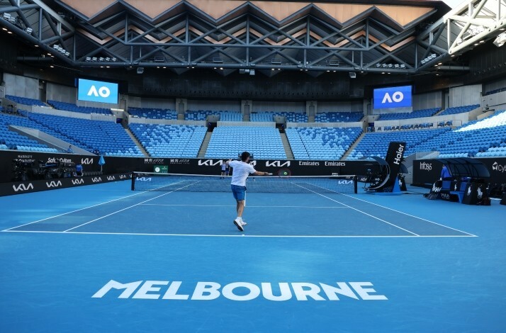 Two people playing tennis in the field at an empty Rod Laver Arena, Melbourne.