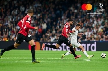 Footballer hitting the ball during UEFA champions league game. Mastercard banner on the background.
