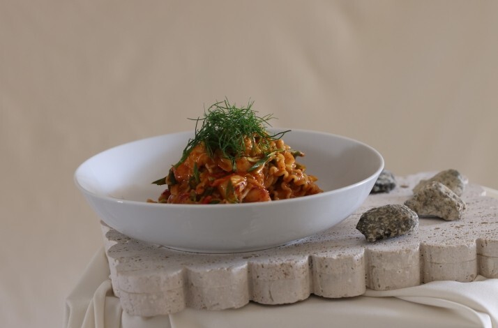 Contemporary Italian pasta dish mounded with herb-garnished tomato ragù, plated on a sculpted stone surface at Cento Pasta Bar.
