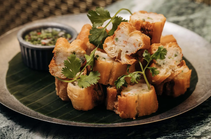 Golden fried bread cubes stacked on a banana leaf, garnished with cilantro and served with dipping sauce at Crying Tiger Chicago.