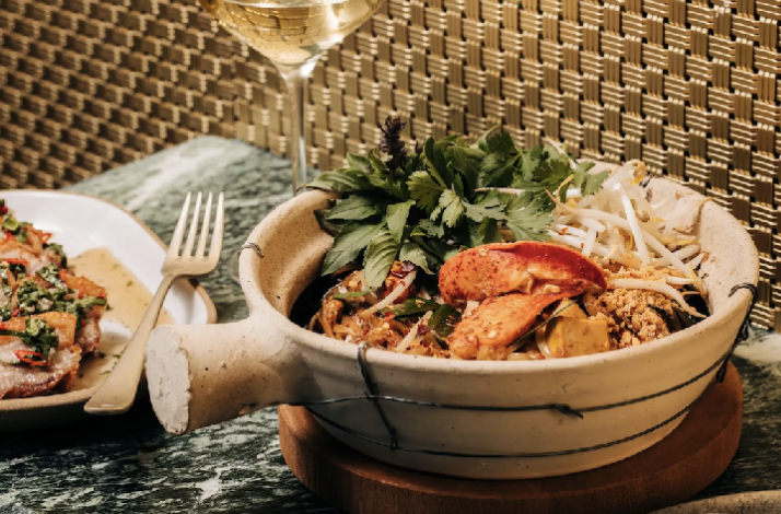 Stone bowl of lobster pad Thai garnished with cilantro and bean sprouts, part of Crying Tiger's Southeast Asian tasting menu.