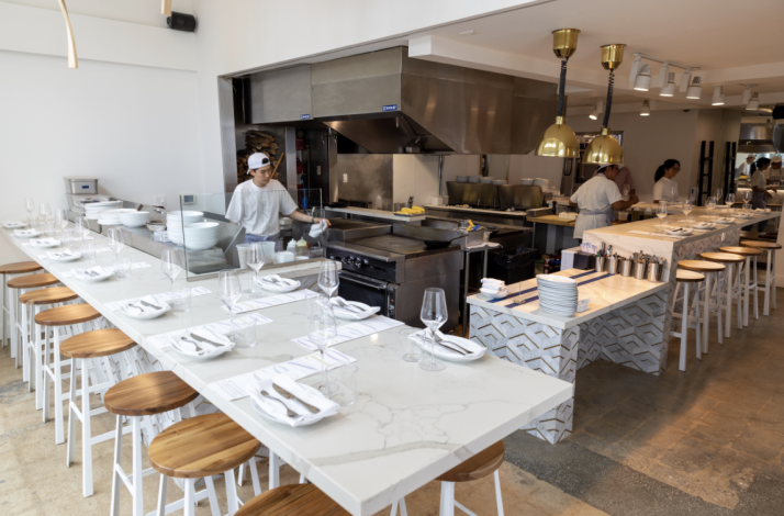 Modern open-kitchen dining room at CENTO Pasta Bar with chefs preparing food.