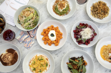 Bird's-eye view of Cento Pasta Bar's multicourse Italian menu, featuring varied pasta shapes, a salad, dessert, and wine pairings.