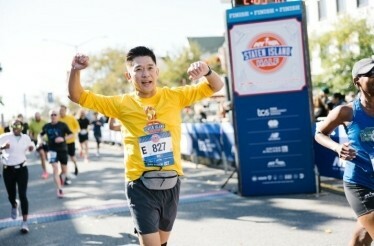 Runner crossing the finish line at the NYRR Staten Island Half marathon, wearing the event bib and race shirt.