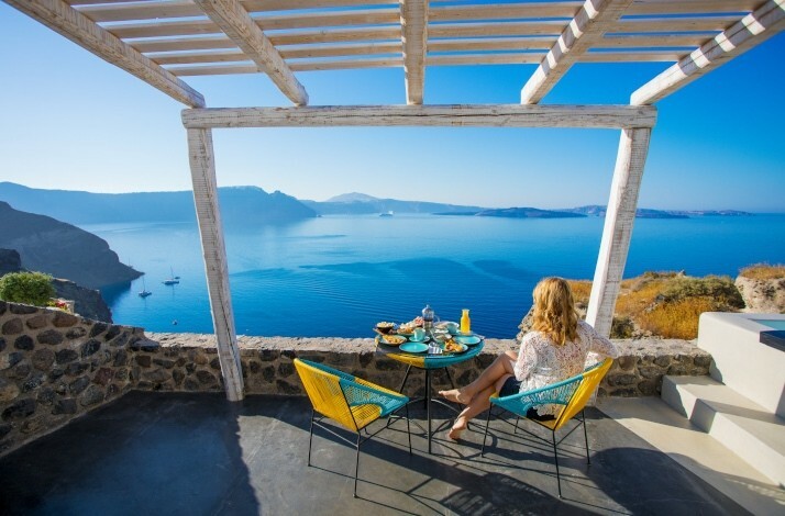 A woman sitting by the table on the terrace with a sea view