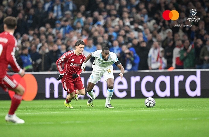 Marseille attacker sprints onto a loose ball as Liverpool defender chases during UEFA Champions League game.