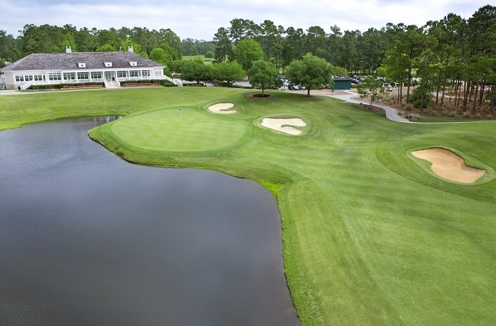 View at TPC Myrtle Beach’s clubhouse surrounded by the golf courses landscape with a pond at the front.