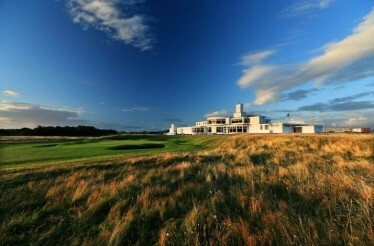 Clubhouse on a golf course under blue sky.