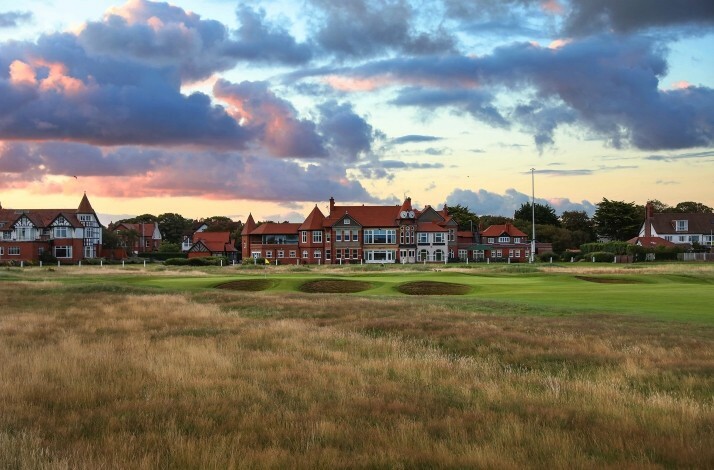 Clubhouse on a golf course under blue sky.