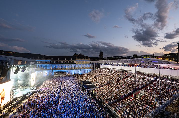 Large crowd gathered at Jazz Open Stuttgart 2026, bathed in colorful stage lights at an open-air night concert.