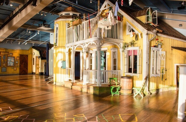 Bright yellow house with white trim inside a play area.