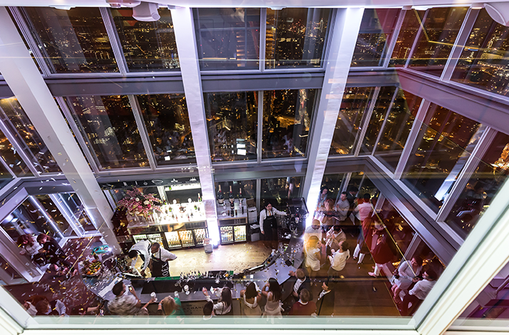 High-angle view of the crowded champagne bar inside The Shard observation deck at night in London, England.