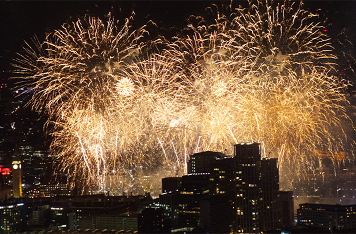 Golden New Year's Eve fireworks lighting up the night sky over the city skyline in London, England.