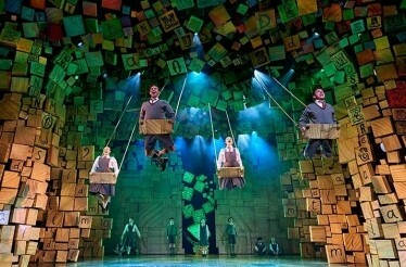Performes on stage swinging on the air during a live production of Matilda The Musical.