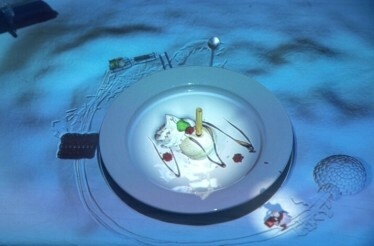 A multimedia presentation of the world's smallest chef finishing dessert on the table at Le Petit Chef.
