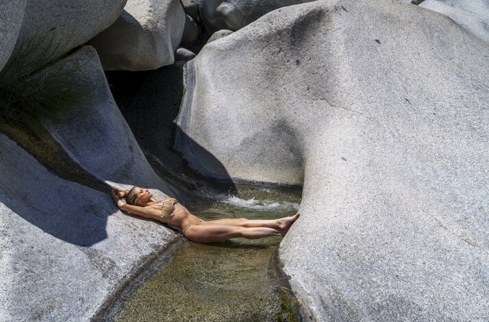 A woman relaxes in a narrow stream surrounded by granite rock formations at Cañón de la Zorra in Mexico's Sierra de la Laguna.