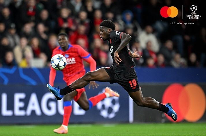 Leverkusen player #19 stretching acrobatically to control the ball during UEFA Champions League 2025/26 match vs PSG.