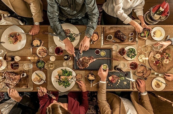 Fully served dinner with wine, steaks and salads at Little London steakhouse in Munich.