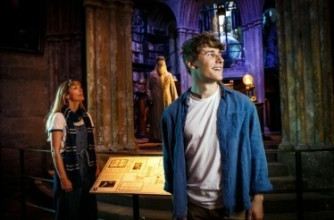 2 people looking at Harry Potter memorabilia during Warner Bros. Studio Tour in London.