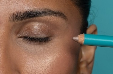 Close-up of a model applying Brown Topaz eyeliner by Cheekbone Beauty.