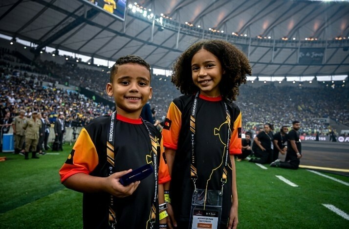 Children in honorary captain uniforms posing on a soccer field