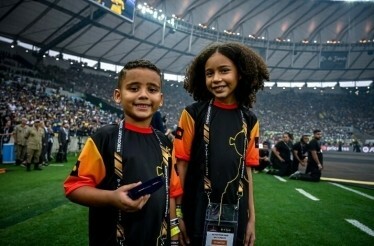 Children in honorary captain uniforms posing on a soccer field