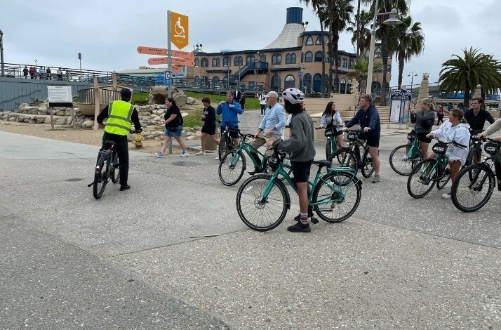 A group of people on Unlimited Biking bicycles stand at a sign.