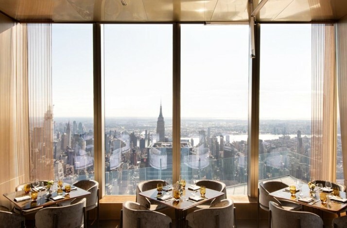 Tables at Peak restaurant on the 101st floor with daytime NYC skyline views.