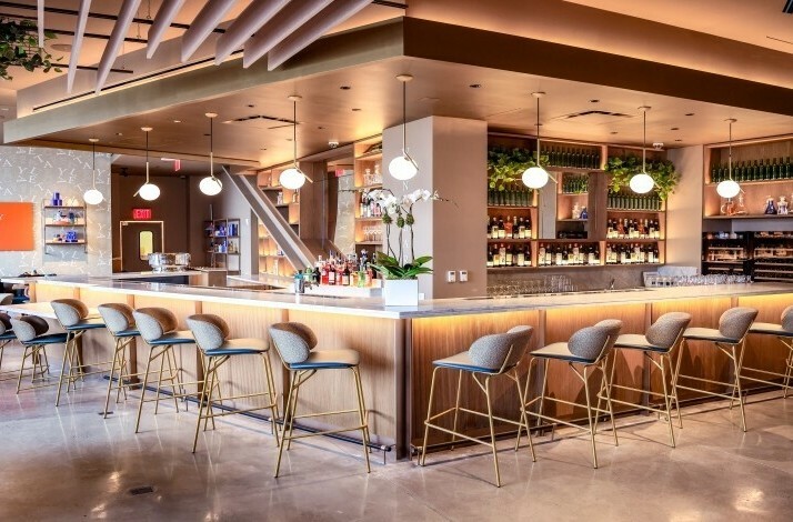 Modern bar area at Eataly Caffè with seating and shelves of bottles.
